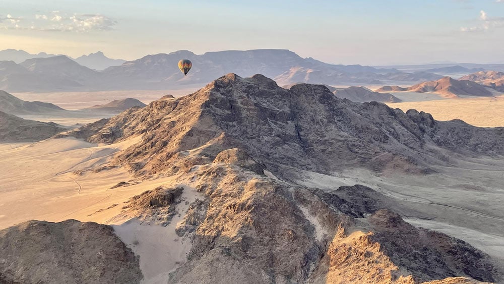 a photograph of a hot air balloon over the desert in Namibia, this is an incredible travel experience